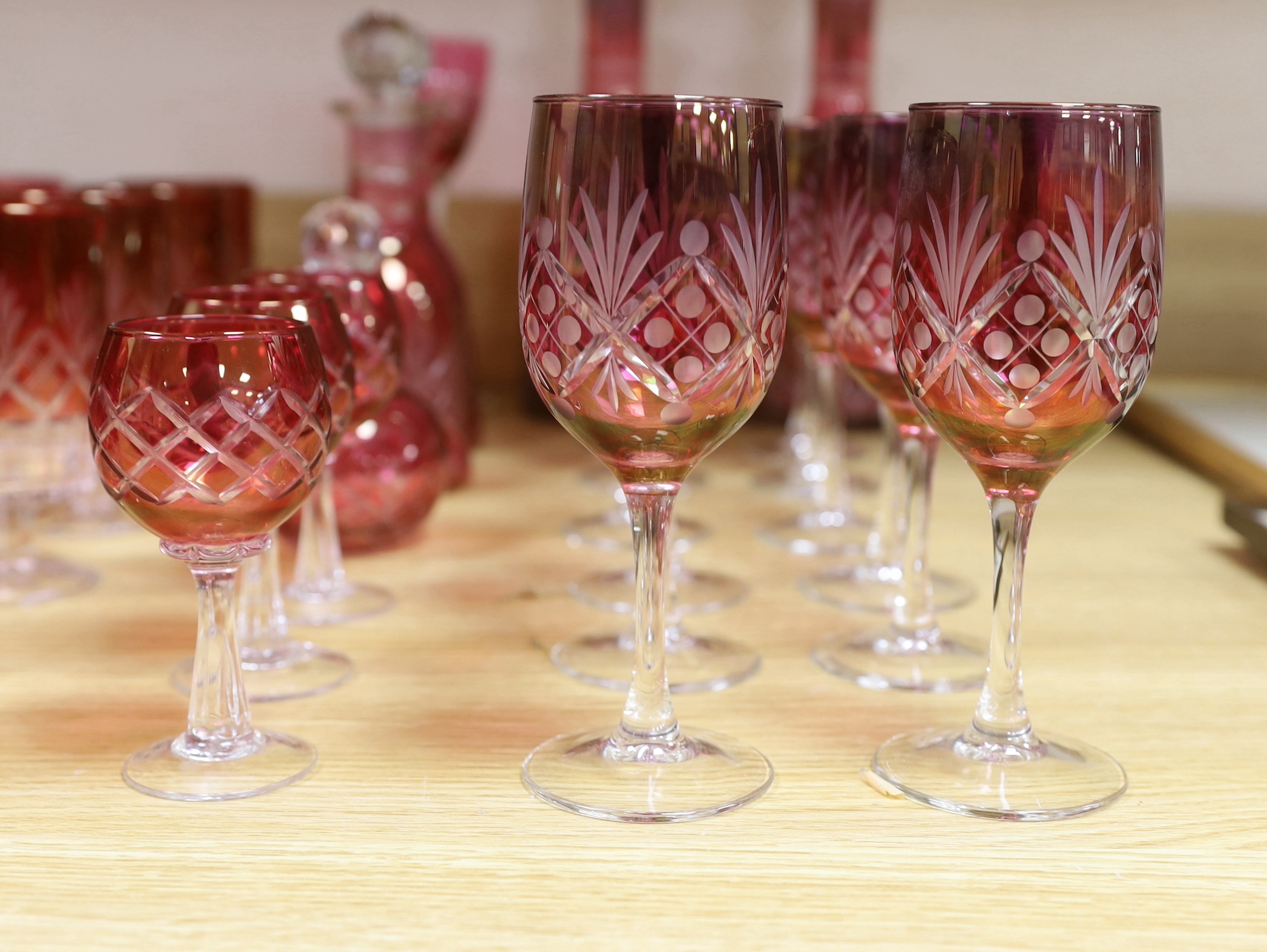 Cranberry glassware including a pair of cut glass decanters, together with a smaller pair and various suites of similar wine glasses, the largest 33cm high